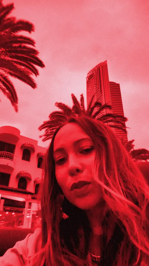 ROMII singing to camera on a Gold Coast street, red-toned still
